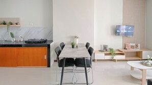 A modern kitchen with a marble countertop, black chairs, and a dining table. - Minimalistic Designed 2Br Nifarro Park Apartment (Jakarta)