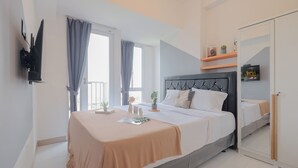 A modern bedroom with a large bed, a bedside table, a mirror, and a TV mounted on the wall. - Comfort And Warm Studio At Tokyo Riverside Pik 2 Apartment (Teluknaga)