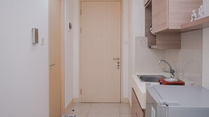 Una cocina compacta con puerta de madera, un lavamanos y un refrigerador.