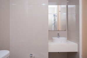 Une salle de bain avec un lavabo blanc, un miroir et des toilettes.