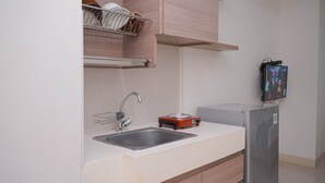 Una cocina moderna con un lavamanos de acero inoxidable, una placa de inducción roja y un refrigerador empotrado.