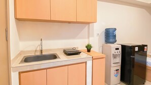 A small kitchenette with a sink, a water dispenser, and a refrigerator.