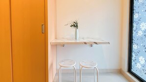A bathroom with a white marble shelf, a white vase with greenery, and two white stools.