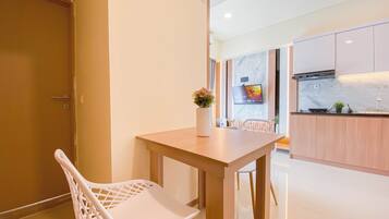 A modern kitchen with a wooden table, white chairs, a TV mounted on the wall, and a small plant on the counter.