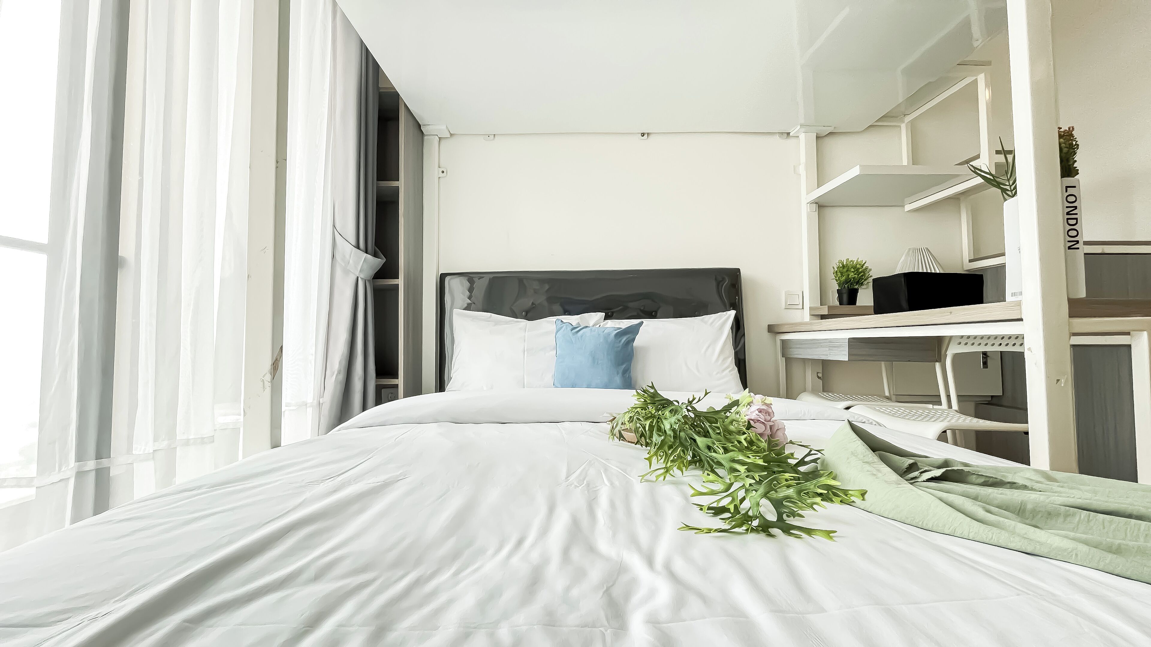 A bedroom with a bed, a desk, and a shelving unit.