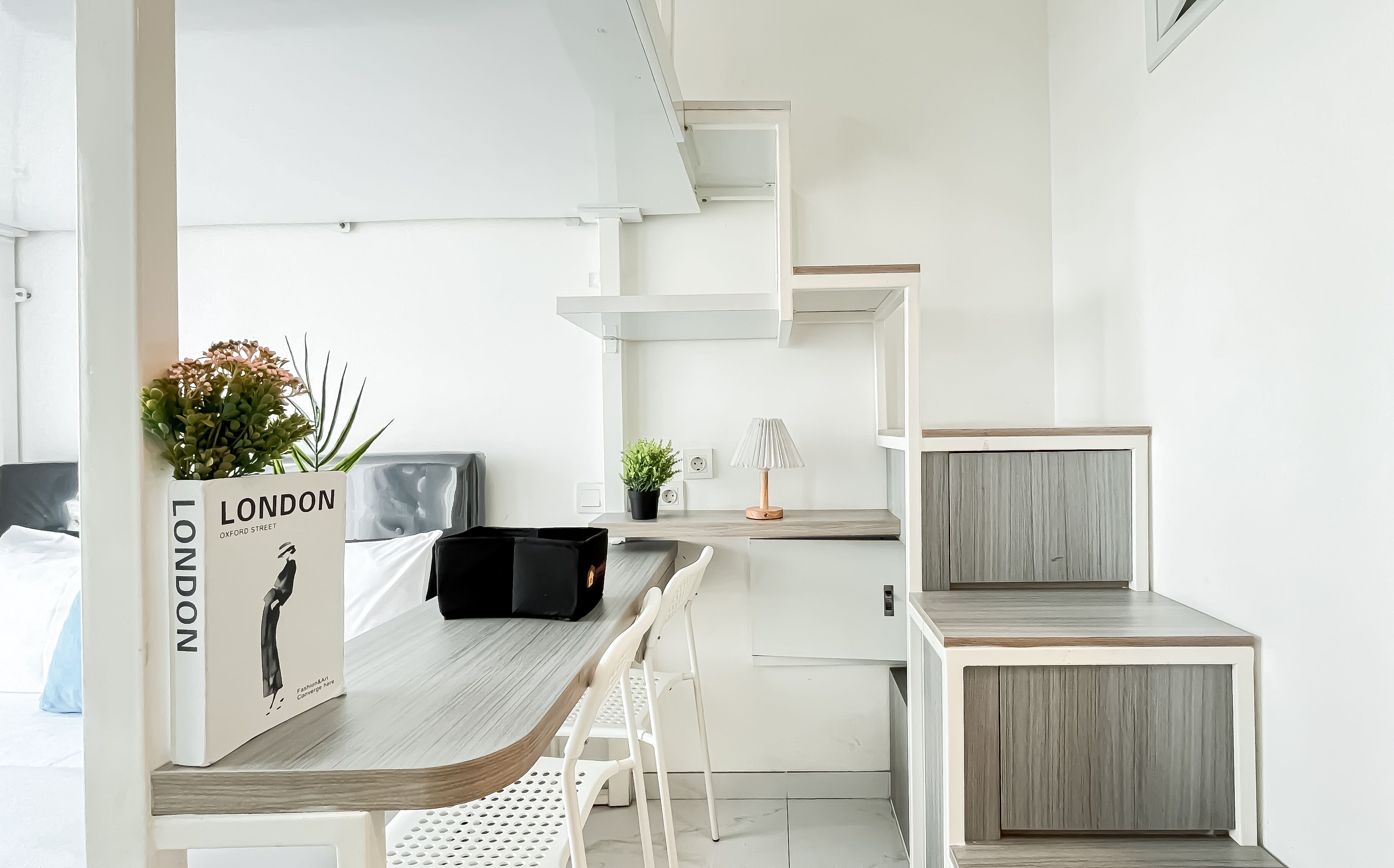 Une cuisine moderne avec des meubles blancs, un plan de travail en bois et une petite plante posée sur le plan de travail.