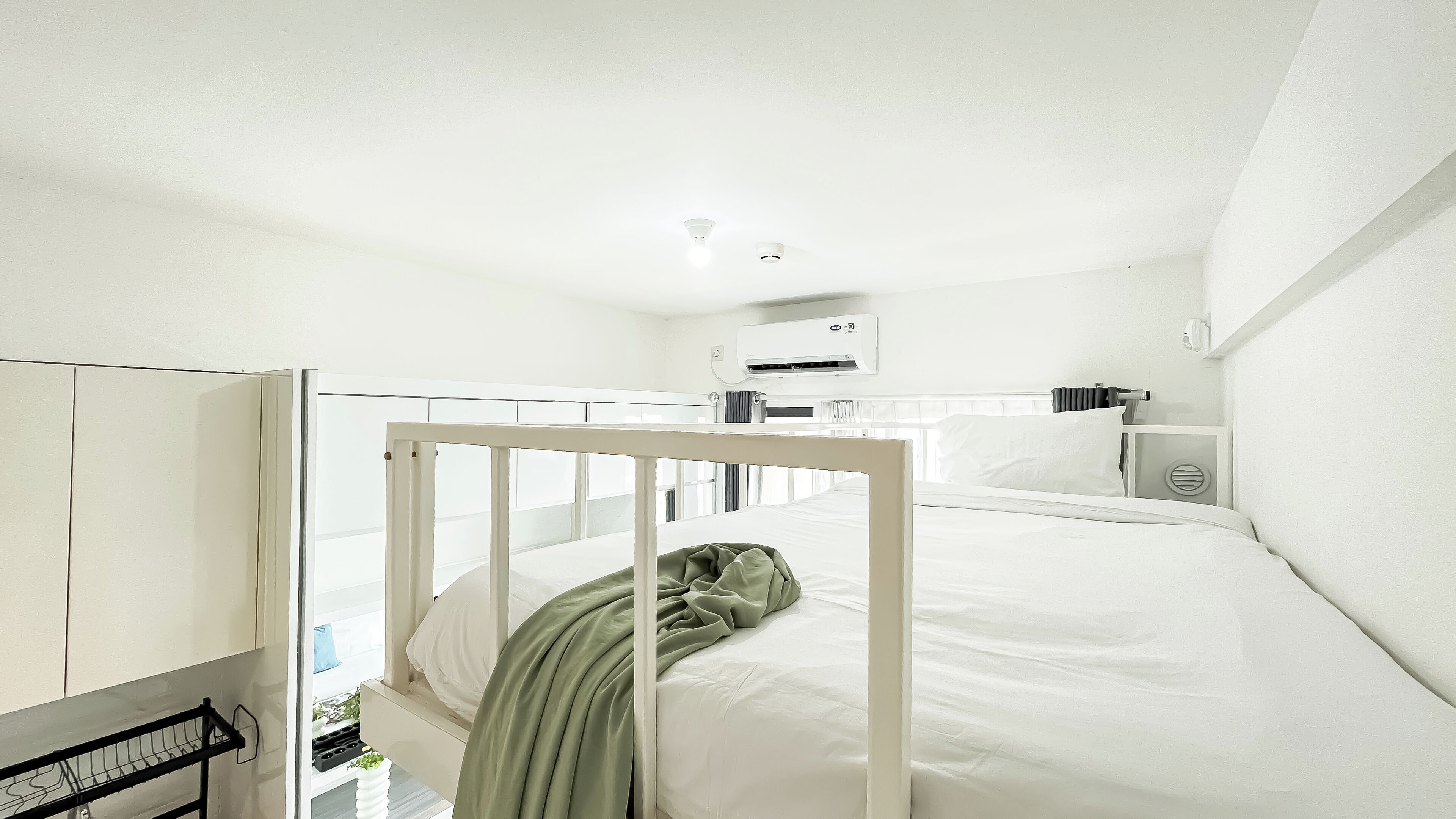 A minimalist hotel room with a bunk bed, a small window, and a white wardrobe.