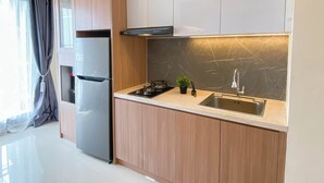 A modern kitchen with wooden cabinets, a stainless steel sink, and a built-in oven. - Best Living 2Br At Meikarta Apartment (Cikarang)