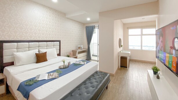 A hotel room with a large bed, a small desk, a TV, and a window with a view. - Great Choice 1Br Apartment At Green Bay Condominium (Jakarta)