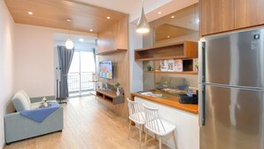 A modern kitchen with wooden cabinets, a stainless steel refrigerator, and a dining area with white chairs. - Great Choice 1Br Apartment At Green Bay Condominium (Jakarta)