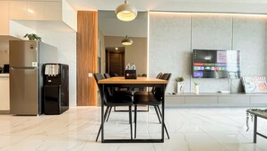 A modern kitchen with a built-in refrigerator, a coffee machine, and a wooden accent wall. - Spacious And Stylish 3Br At Sky House Bsd Apartment (Pagedangan)