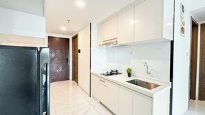 A modern kitchen with white cabinets, a stainless steel sink, and a black refrigerator.