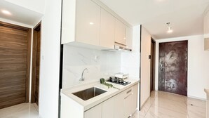 A modern kitchen with a marble backsplash, stainless steel sink, and a built-in stove. - Quiet And Homey 2Br With Extra Room Apartment Sky House Bsd (Pagedangan)