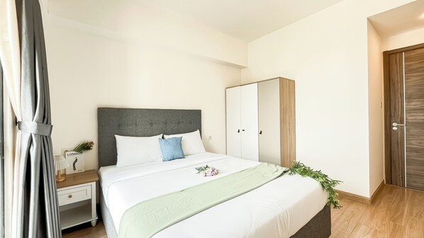 Une chambre à coucher bien rangée, avec un lit, une table de chevet, une armoire et une porte.
