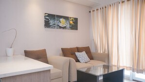 A modern living room with a sofa, a coffee table, and a painting on the wall. - Comfy And Modern 1Br Apartment Paramount Skyline (Gading Serpong)