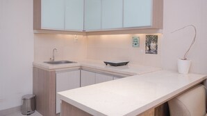 A modern kitchen with white cabinets, a sink, a scale, and a potted plant. - Comfy And Modern 1Br Apartment Paramount Skyline (Gading Serpong)