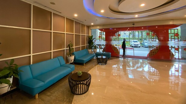 A modern lobby with blue sofas, a coffee table, and a large glass entrance. - Comfy And Modern 1Br Apartment Paramount Skyline (Gading Serpong)