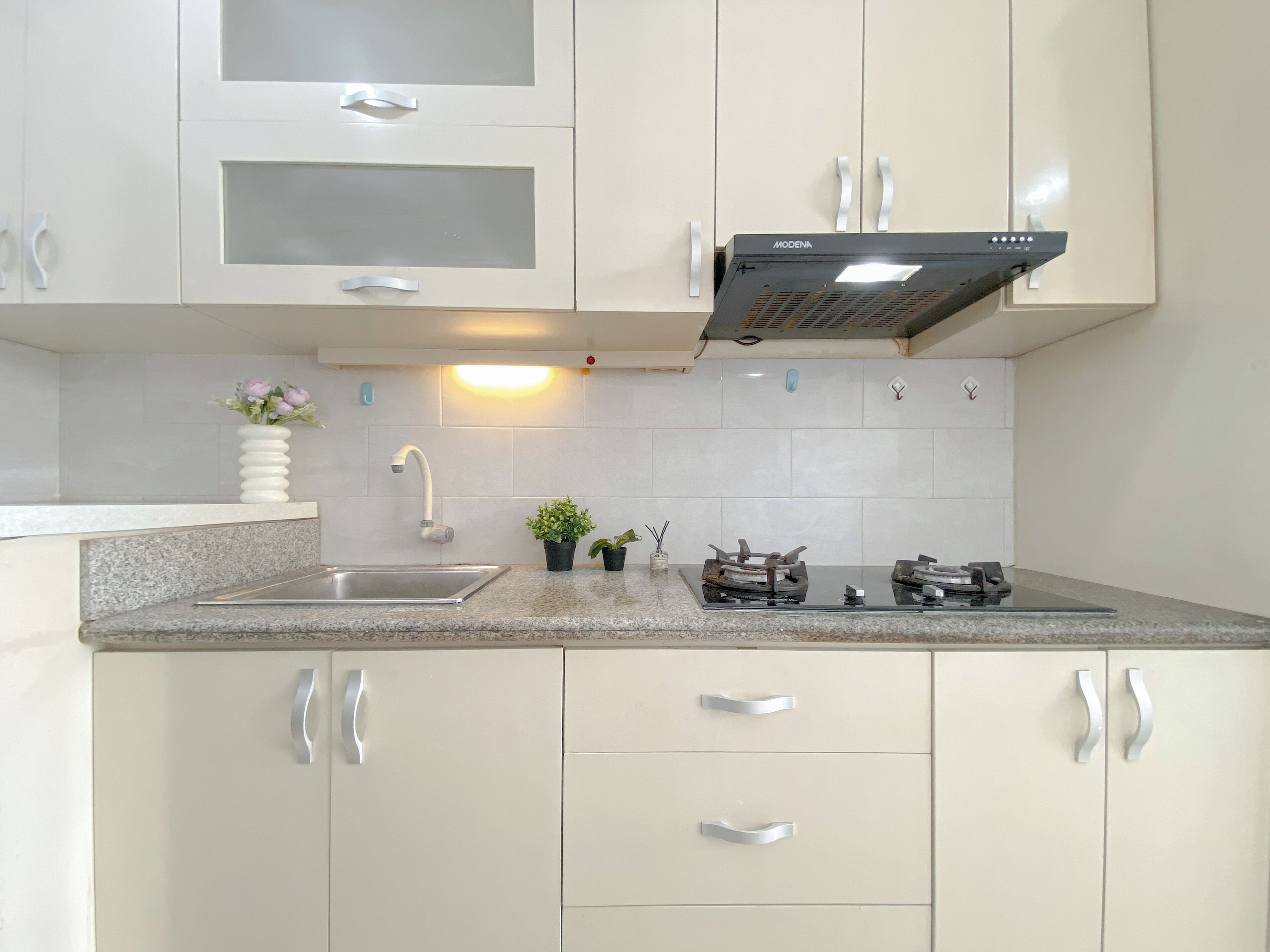 A modern kitchen with white cabinets, a granite countertop, a gas stove, and a stainless steel sink.