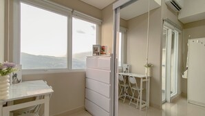 Eine moderne Küche mit großem Fenster, weißen Schränken und einem Essbereich mit weißem Tisch und Stühlen.