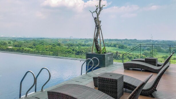 Ein Pool ohne erkennbarem Ende mit Liegestühlen und Blick auf eine grüne Landschaft.