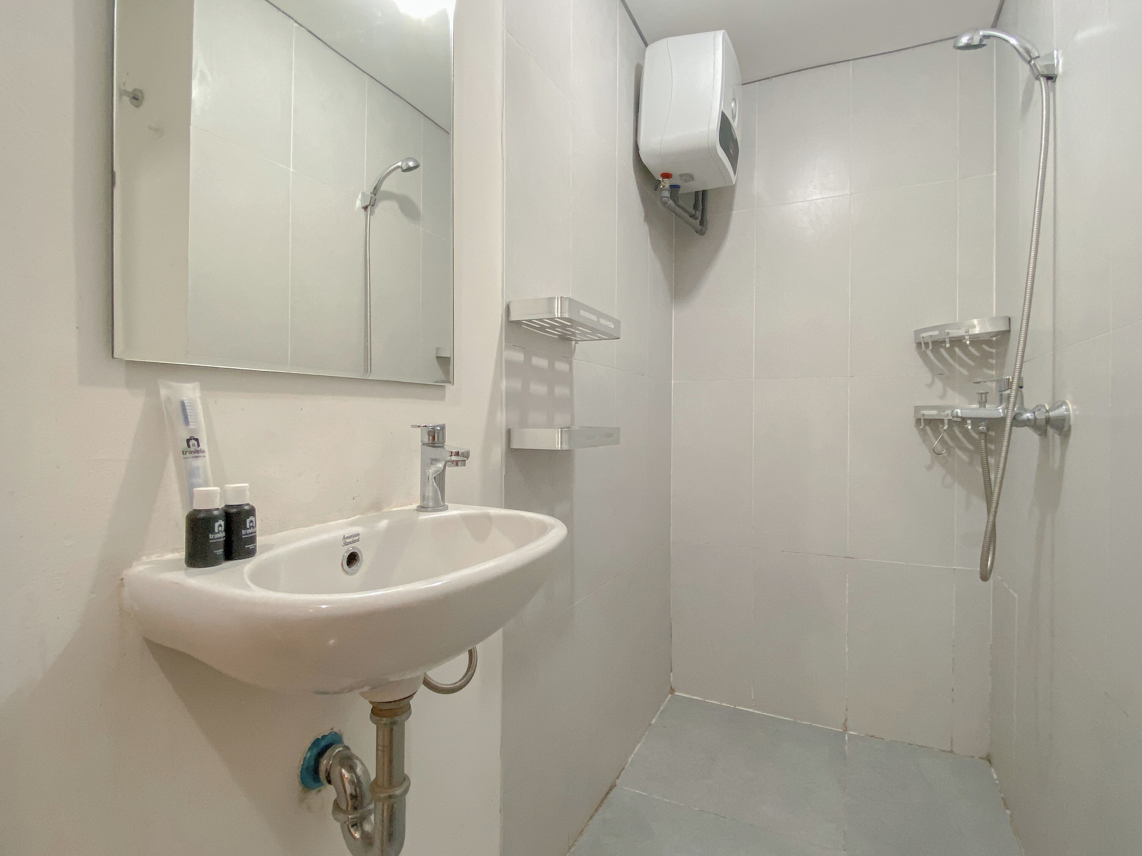 A bathroom with a white sink, a mirror, a handheld showerhead, and a soap dispenser.