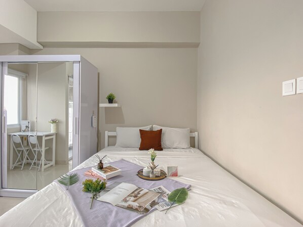 A modern bedroom with a bed, a bedside table, a small desk, and a chair.