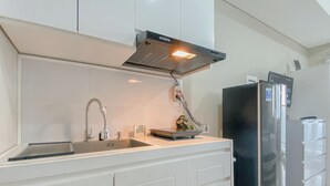 Eine Küche mit weißen Schränken, einer Edelstahl-Spüle, einem schwarzen Kühlschrank und einer eingebauten Dunstabzugshaube.