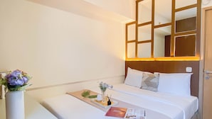 A hotel room with a bed, bedside table, and a wall-mounted mirror. - Modern Look And Restful 3Br At Meikarta Apartment (Cikarang)