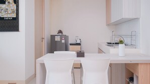 A modern kitchen with a dining table and chairs, a refrigerator, a coffee maker, and a sink. - Modern Look And Homey 2Br Apartment Tree Park City Bsd (South Tangerang)