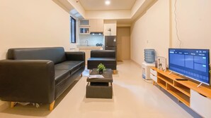 A modern living room with a sofa, a coffee table, and a TV on a wooden stand. - Good Deal And Comfy 2Br Apartment Meikarta (Cikarang)