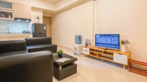 A modern living room with a flat-screen TV, a sofa, a coffee table, and a small side table. - Good Deal And Comfy 2Br Apartment Meikarta (Cikarang)