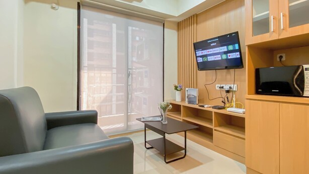 A modern office space with a desk, chair, and a mounted TV displaying various apps. - Cozy And Minimalist 1Br With Working Room Meikarta Apartment (Cikarang)