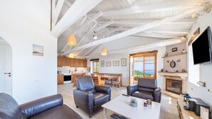 A spacious living area with leather sofas, a white coffee table, and a fireplace.