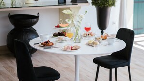 Een eettafel met stoelen, een vaas met bloemen en diverse gerechten en drankjes.