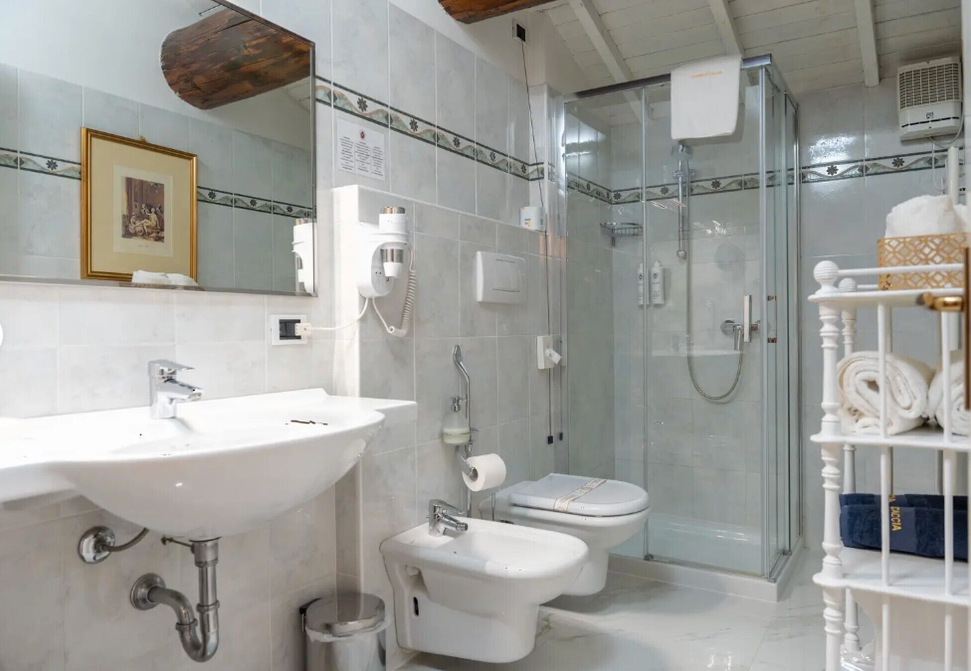 A bathroom with a sink, bidet, toilet, and glass-enclosed shower.