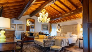 A cozy room with a bed, a sofa, a dining table, and a chandelier.