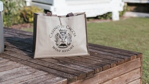 A wooden bench with a bag labeled 'CASINO DI CACCINO WINE RESORT' in front of a white outdoor seating area with a canopy. - Room 'Casino Di Caccia 6' with Shared Pool, Wi-Fi and Air Conditioning (Sommacampagna)