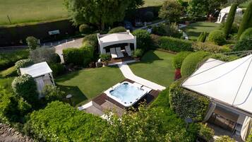 Ein privater Garten mit Whirlpool, Laube und überdachter Terrasse.