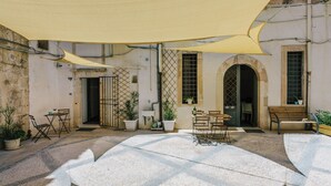 A courtyard with outdoor seating, potted plants, and a large canopy providing shade. - 1743LOft Cortiletto (Siracusa)