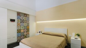 A modern bedroom with a large bed, a bedside table with a lamp, and a colorful tile wall. - 1743LOft Cortiletto (Siracusa)