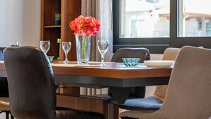A dining area with a wooden table, chairs, and a vase with flowers.