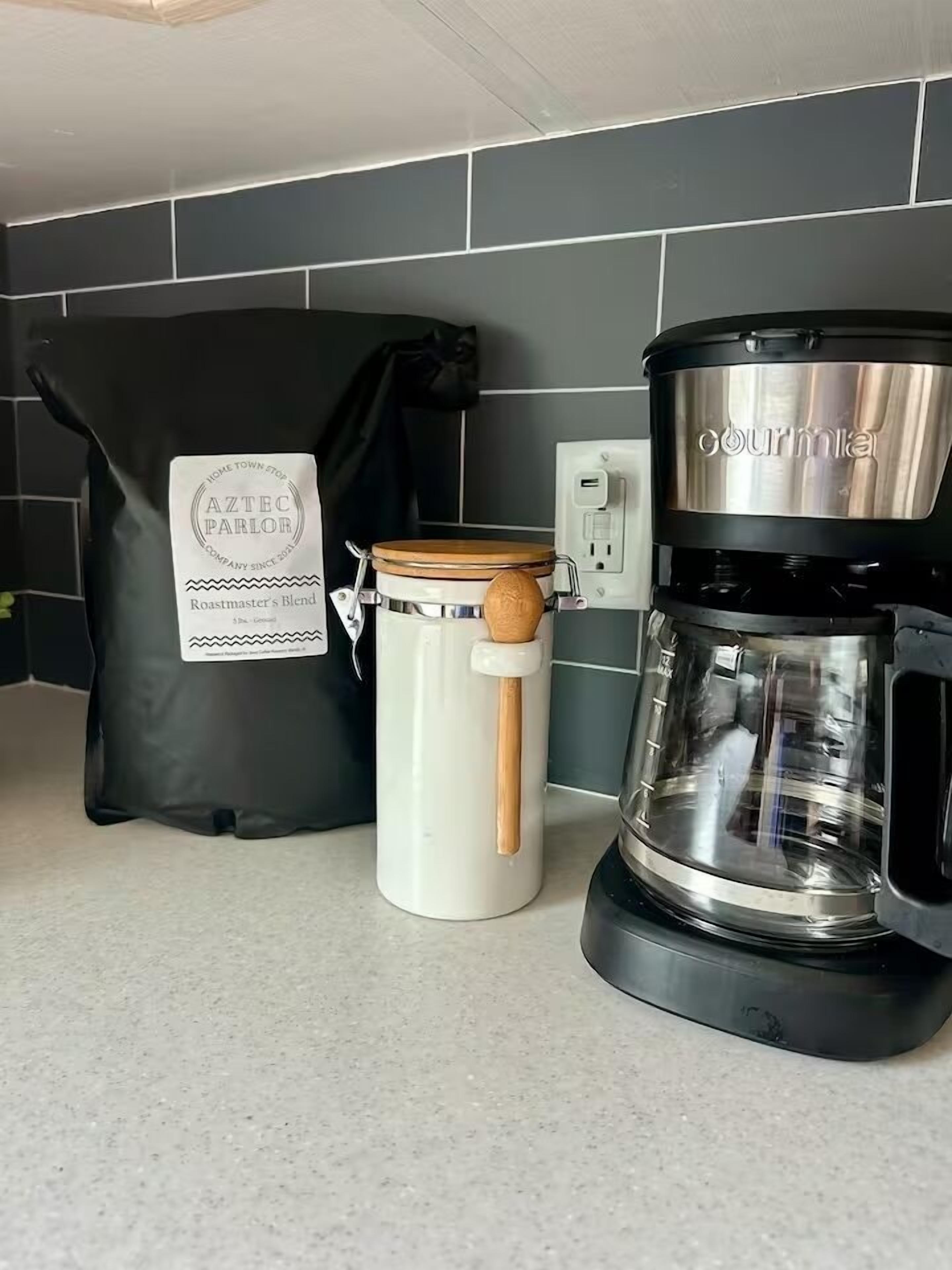 Una cucina con una macchina da caffè, un bollitore e un sacchetto di chicchi di caffè.