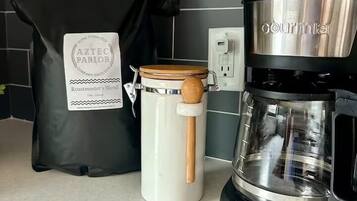 Una cucina con una macchina da caffè, un bollitore e un sacchetto di chicchi di caffè.