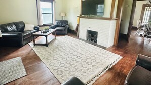 Ein Wohnzimmer mit Kamin, Ledersofas, einem Couchtisch und einem Fernseher, der über dem Kamin angebracht ist.