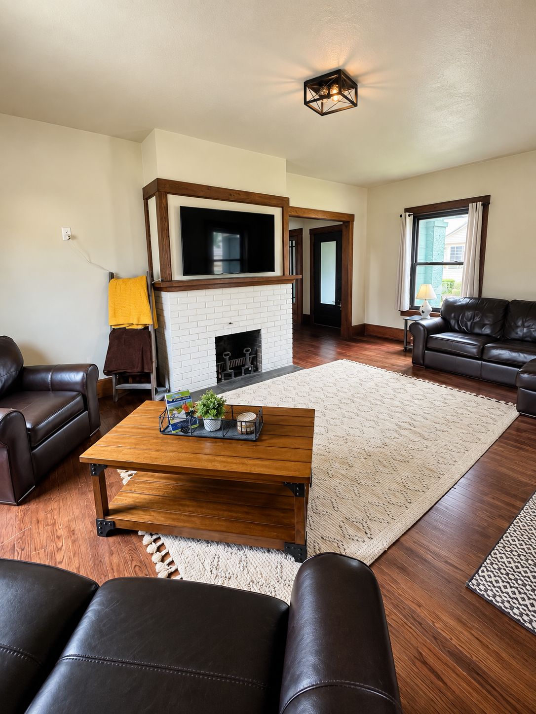 A living room with a fireplace, leather sofas, a coffee table, and a large window.