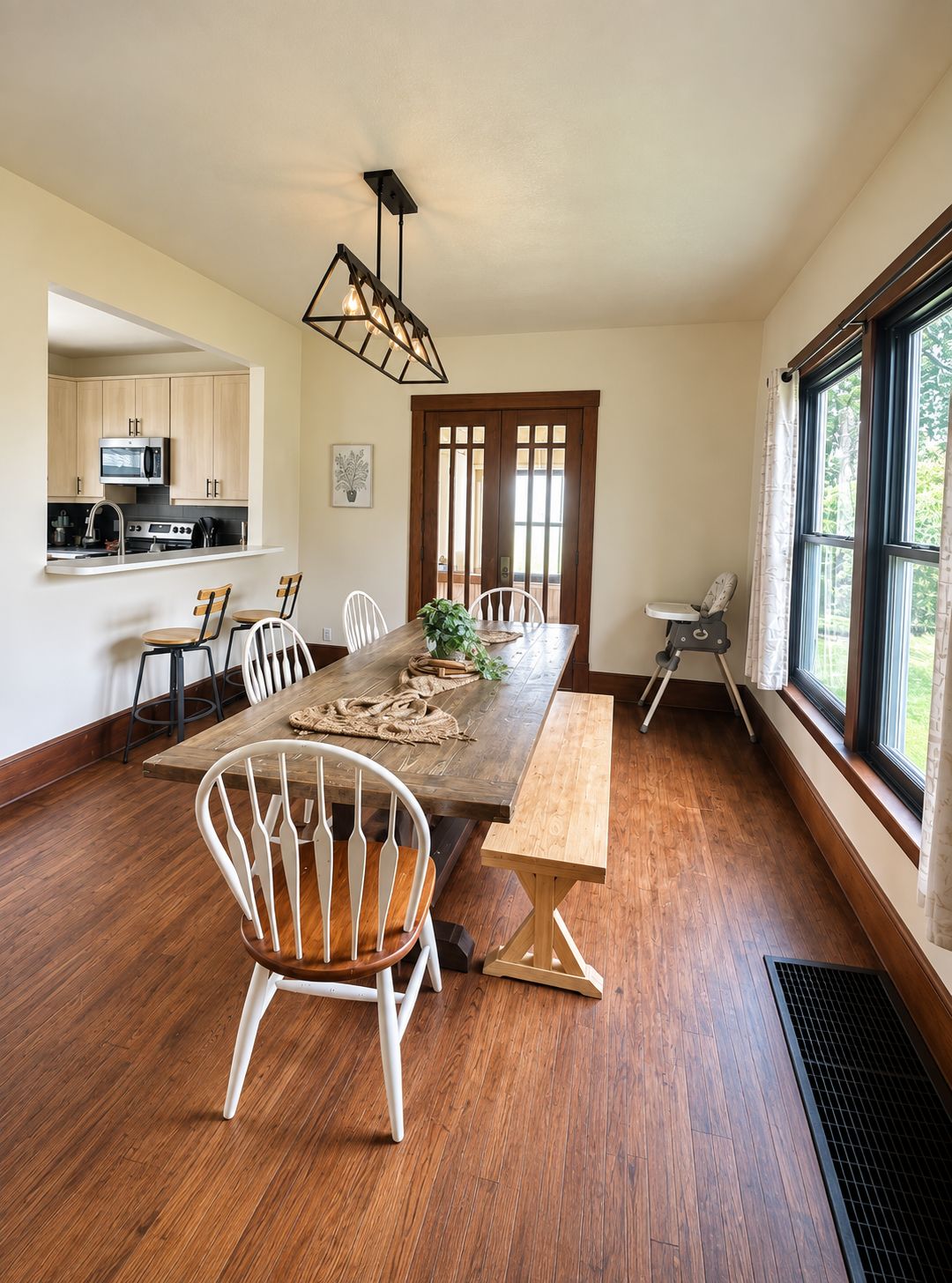 A dining area with a wooden table, white chairs, and a kitchen in the background.
