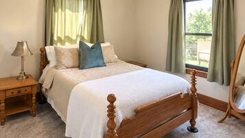 A bedroom with a wooden bed, a nightstand, a lamp, a ceiling fan, and curtains.