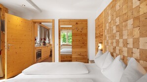 A bedroom with a wooden headboard, a bed with white bedding, and a view of a wooden wall and a window. - Apartment 'Hotel Residence Olympia 4' with Mountain View, Shared Garden and Wi-Fi (Sarnthein)