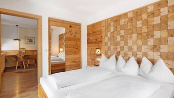 A room with a wooden headboard, a bed with white bedding, a desk with a chair, and a mirror.