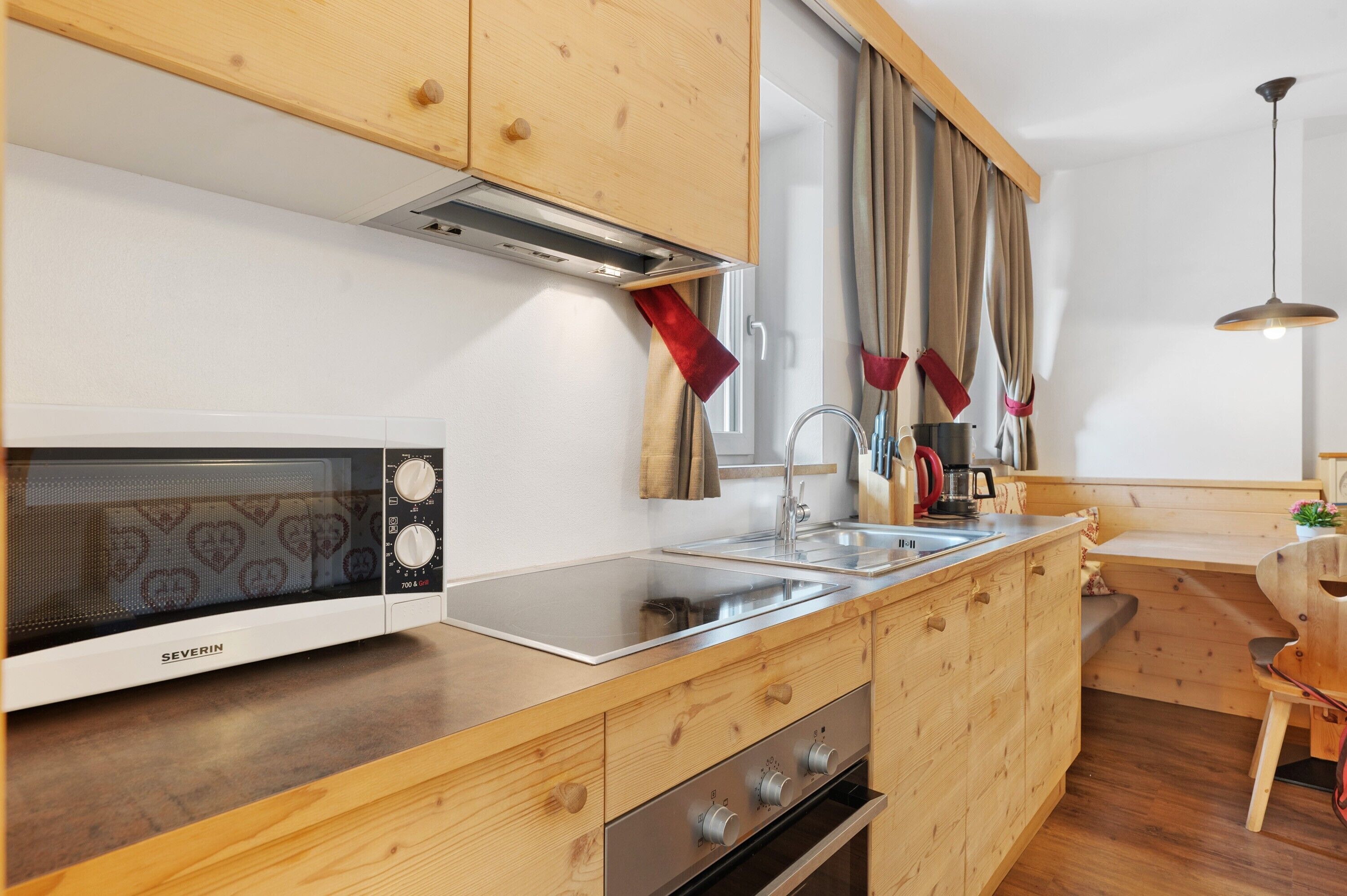 Una cocina moderna con armarios de madera, microondas, lavaplatos y estufa.